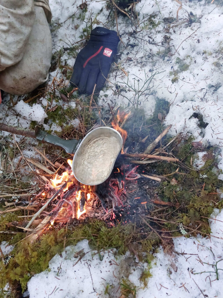 Pakissa kiehuu vesi nuotion päällä lumessa.
